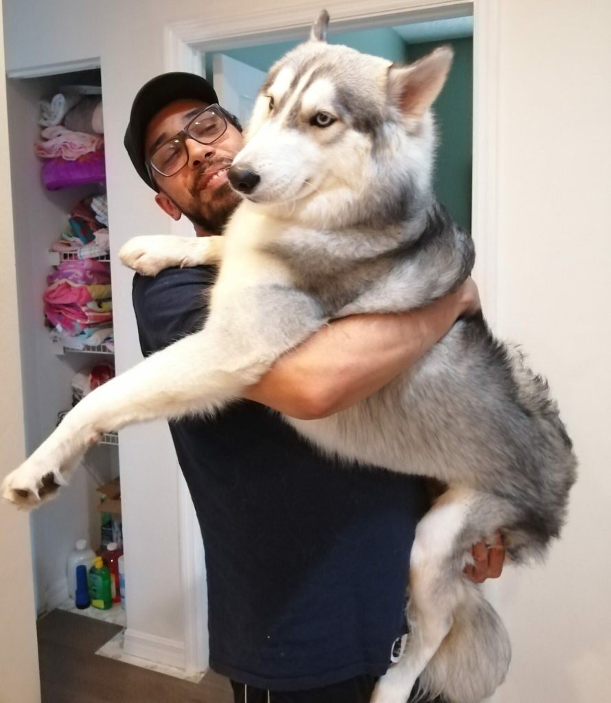 Erik holding Duke, his rescue Husky, in the doorway at home in Broward County, Florida